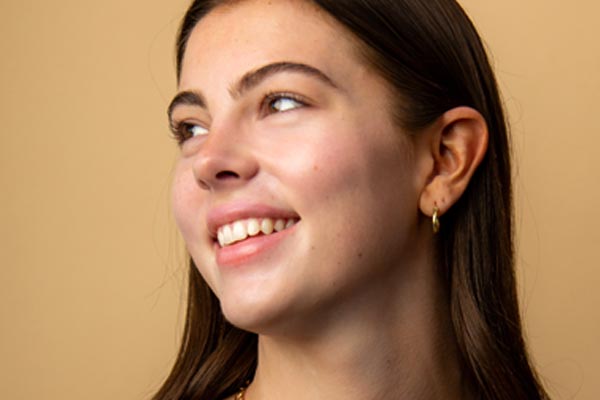 Image of models face after applying Cotz Sensitive Non-Tinted SPF 40 to show off glowy finish