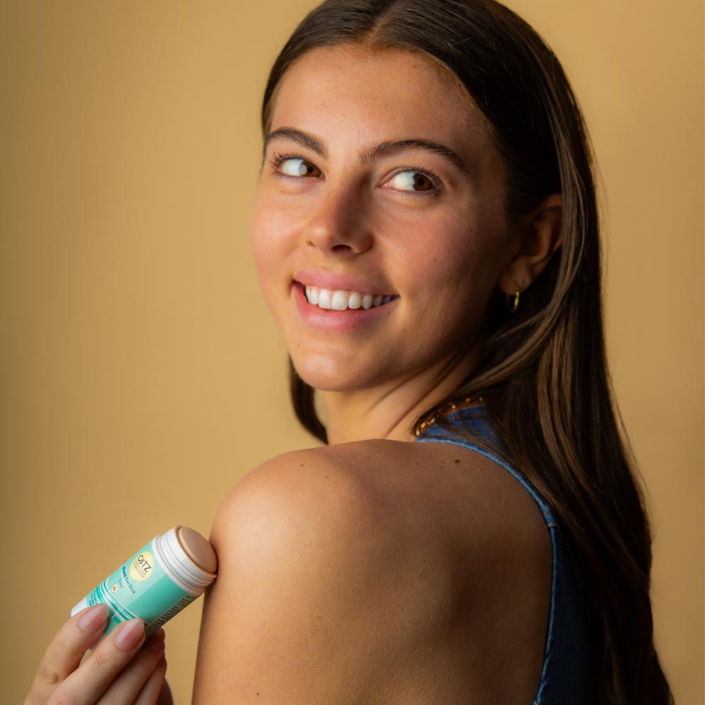 Image of model looking over her shoulder applied Cotz Mineral Sun Stick Tinted SPF 45 on her shoulder