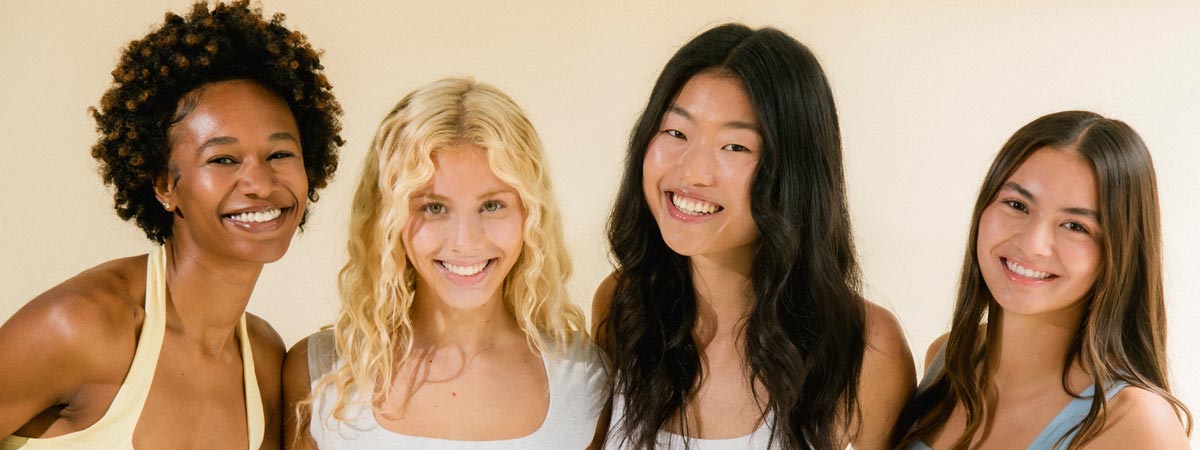 Image of four models side by side hugging each other while smiling with dewy skin with Cotz Mineral Sun Stick SPF 45 applied