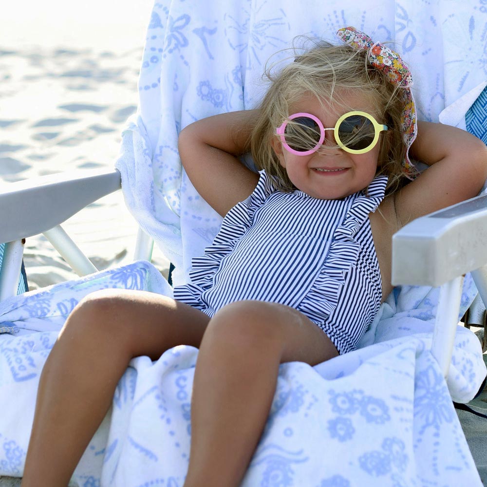 Image of a blonde kid with sun glasses on lounging in a beach chair with Cotz Baby Non-Tinted SPF 40 applied