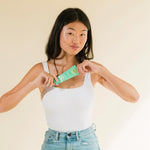 Model holding Cotz Sensitive Non-Tinted SPF 40 near her chest while smiling